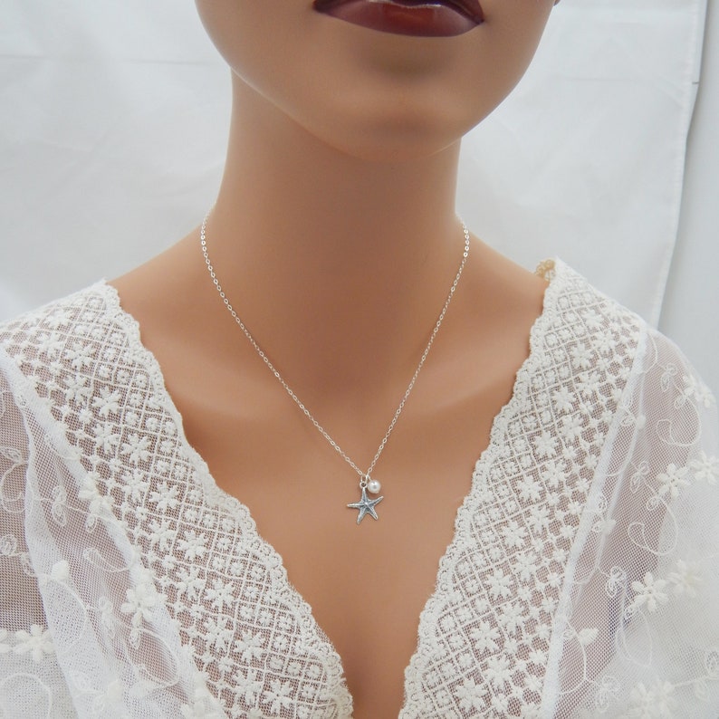 Puede incluir: Un collar de cadena de plata con una peque&ntilde;a perla y un dije de estrella de mar de plata.