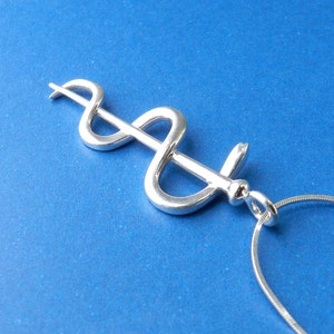 May include: A silver medical caduceus pendant necklace on a silver chain. The caduceus is a symbol of medicine and healing.