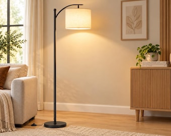May include: A tall floor lamp with a slender black metal pole and a circular base. The lamp features a curved top arm that holds a cylindrical, off-white fabric drum shade, which emits a warm, soft glow when illuminated.