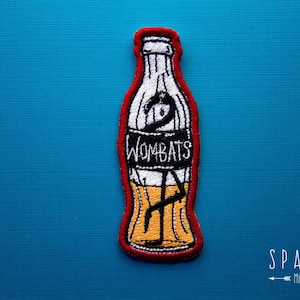 May include: Red, white, and yellow embroidered patch of a soda bottle with the text "Wombats" on it.