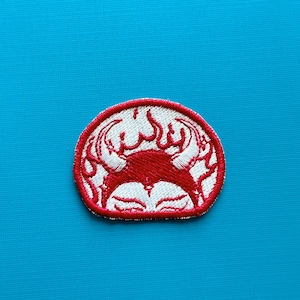 May include: Embroidered patch with a red crab design and white detailing, set against a white background within a red circular border. The crab has a stylized appearance with flames. Suitable for clothing or accessories.