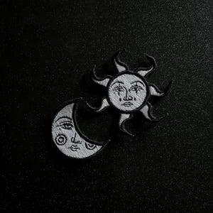 Puede incluir: Parches de hierro bordados en blanco y negro de un sol y una luna creciente con caras.