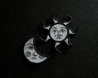 May include: Black and white embroidered iron-on patches of a sun and a crescent moon with faces.