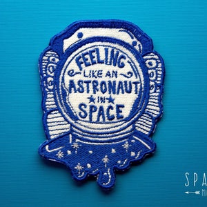 May include: Blue embroidered patch with a white astronaut helmet and the text "Feeling like an astronaut in space".