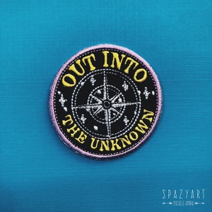 May include: A pink and yellow embroidered patch with a compass and the text "Out into the unknown".
