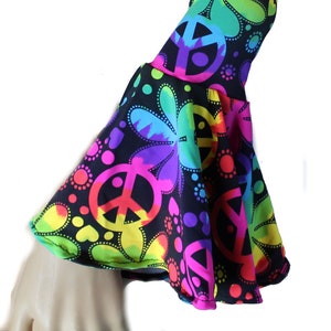 May include: A black arm warmer with a rainbow peace sign and flower pattern. The arm warmer has a bell bottom style.