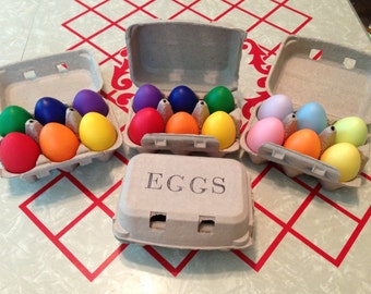 May include: Three cardboard egg cartons filled with colorful painted eggs. The cartons are labeled "EGGS".