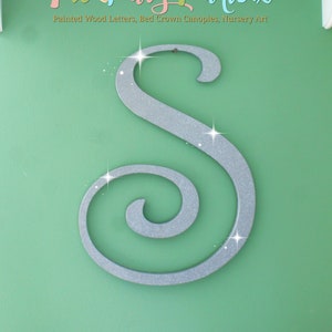 Puede incluir: Una letra S de purpurina plateada con un diseño de espiral, en una pared verde. El logotipo de The Fairy Paintbox está encima de la letra, con el texto "Painted Wood Letters, Bed Crown Canopies, Nursery Art".