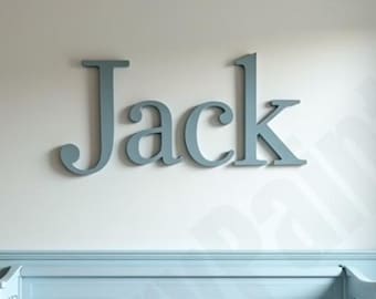 May include: A wall decoration spelling the name "Jack" in large, stylized, pale blue letters. The letters are mounted on a white wall above a pale blue painted trim and a matching headboard.