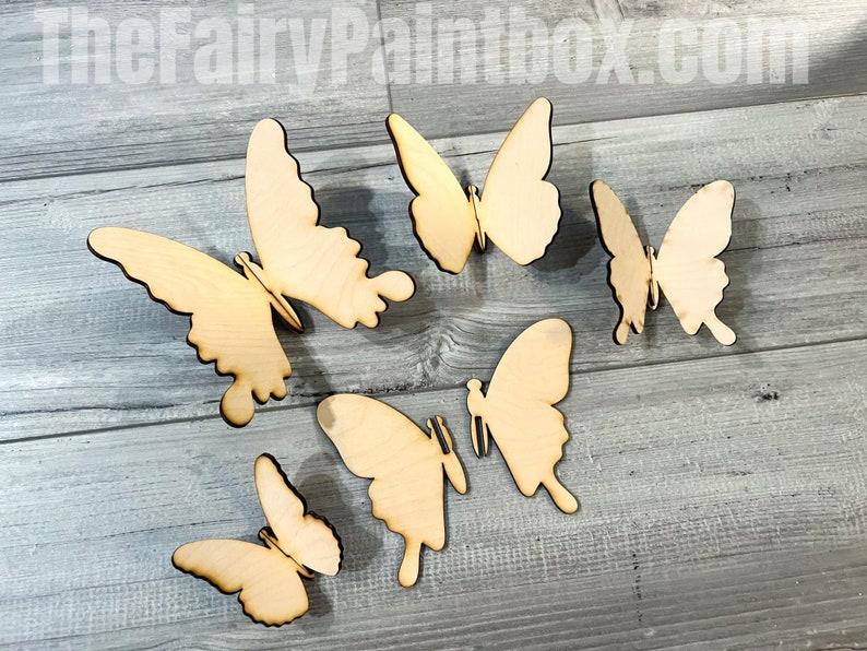 May include: Five unfinished wooden butterfly shapes, perfect for crafting and decorating. The butterflies are various sizes and are arranged on a light wood surface.