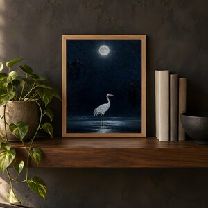 Moonlit crane print in the 8x10 inch size on a dark wooden shelf with books and a plant; the frame shown is not included.
