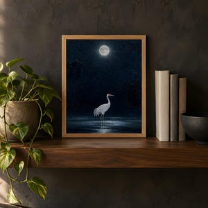 Moonlit crane design printed in the 8x10 inch size on a dark wooden shelf with books and a plant; the frame shown is not included.