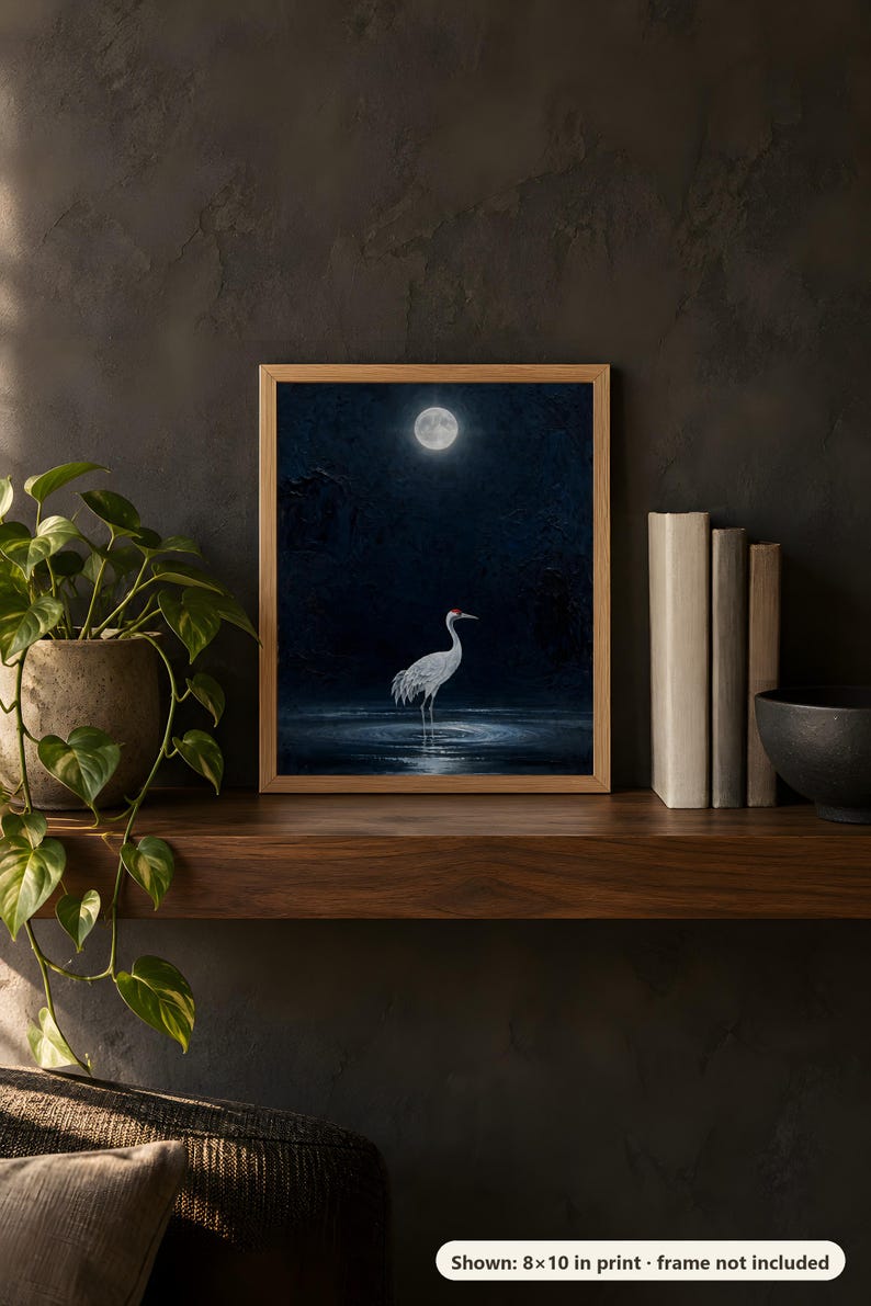 Moonlit crane design printed in the 8x10 inch size on a dark wooden shelf with books and a plant; the frame shown is not included.