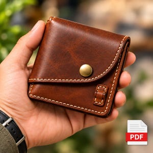 May include: A brown leather wallet featuring a curved flap closure secured with a single brass-toned metal snap button. The wallet is accented with visible white contrast stitching along the edges and includes a small rectangular loop.
