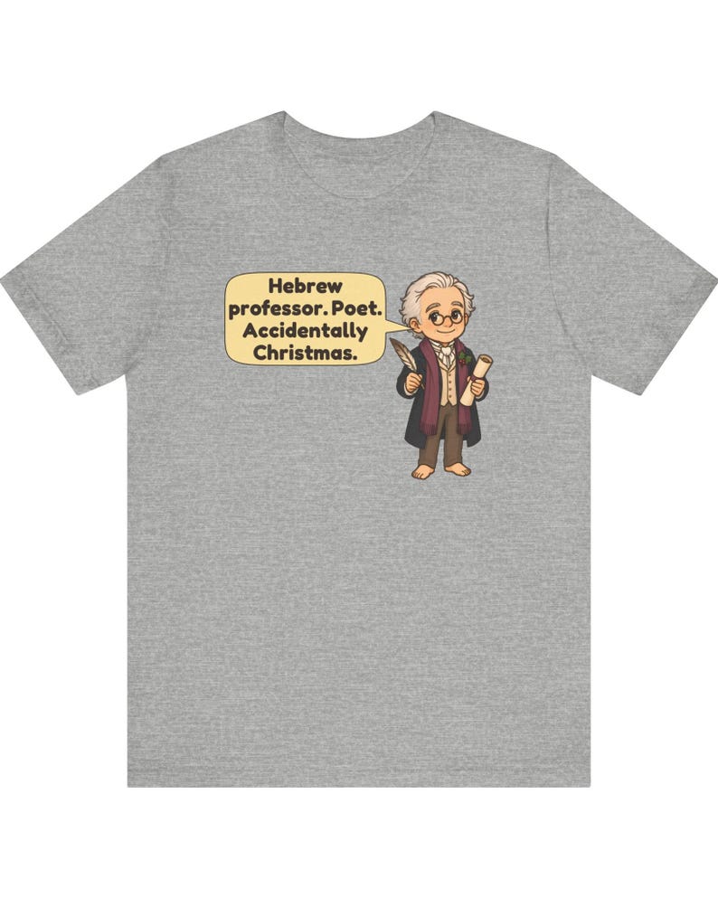 Pu&ograve; includere: Una t-shirt grigio melange con un'illustrazione a cartone animato di un professore che tiene in mano una penna e una pergamena. Un fumetto accanto al personaggio contiene il testo: Hebrew professor. Poet. Accidentally Christmas.