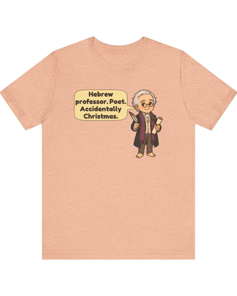 Pu&ograve; includere: Una t-shirt a maniche corte color pesca m&eacute;lange con un'illustrazione a cartone animato di un personaggio che tiene una penna e una pergamena. Un fumetto contiene il testo: Hebrew professor. Poet. Accidentally Christmas.