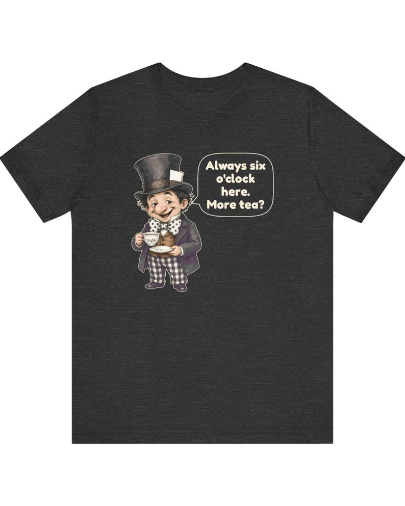 May include: A dark heather gray t-shirt featuring a graphic of a character wearing a top hat, a brown vest, and checkered pants, holding a teacup. A speech bubble next to the character contains the text: Always six o'clock here. More tea?