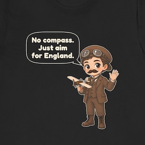 May include: A black t-shirt featuring a cartoon illustration of an aviator with a mustache, wearing a brown suit, cap, and goggles. The aviator holds a small airplane and a speech bubble with the text: No compass. Just aim for England.