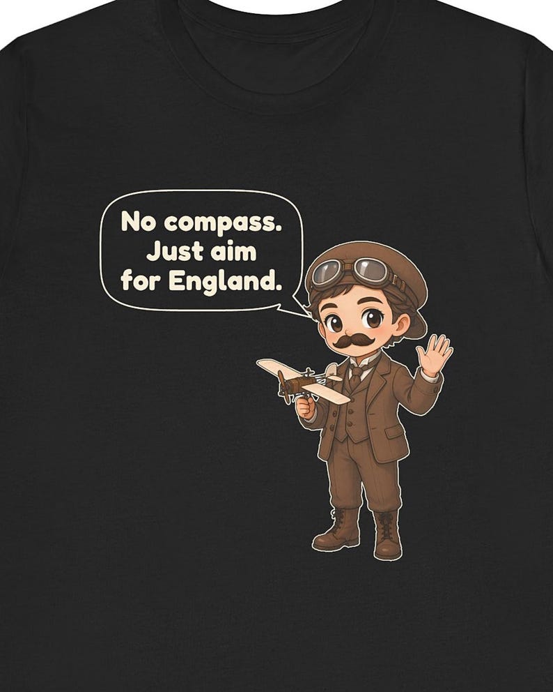 May include: A black t-shirt featuring a cartoon illustration of an aviator with a mustache, wearing a brown suit, cap, and goggles. The aviator holds a small airplane and a speech bubble with the text: No compass. Just aim for England.