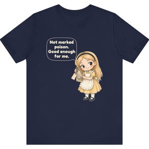 May include: A navy blue t-shirt featuring a cartoon illustration of a blonde character in a yellow dress and white apron holding a glass bottle. A speech bubble above the character contains the text: Not marked poison. Good enough for me.