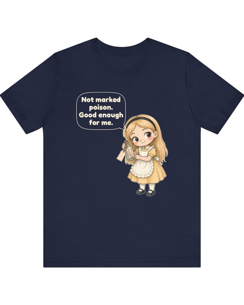 May include: A navy blue t-shirt featuring a cartoon illustration of a blonde character in a yellow dress and white apron holding a glass bottle. A speech bubble above the character contains the text: Not marked poison. Good enough for me.