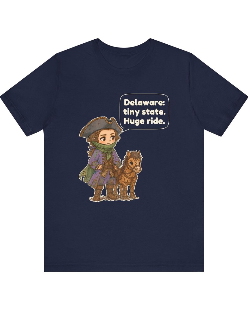 May include: A navy blue t-shirt featuring a graphic of a person in a historical tricorn hat and purple coat standing next to a small brown horse. A speech bubble above them contains the text: Delaware: tiny state. Huge ride.