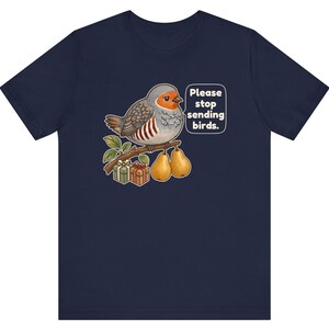 K&ouml;nnte beinhalten: Ein marineblaues T-Shirt mit einer Grafik eines grauen und orangefarbenen Vogels, der auf einem Ast mit zwei Birnen und zwei Geschenkkartons sitzt. Eine Sprechblase neben dem Vogel enth&auml;lt den wei&szlig;en Text, Please stop sending birds.