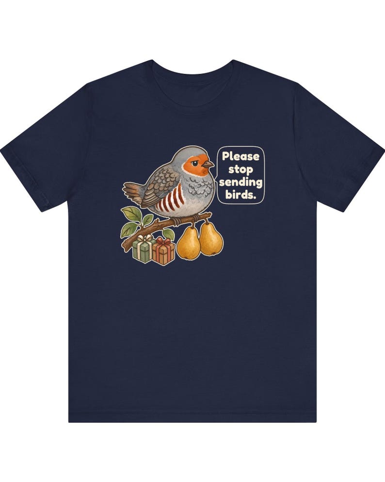 K&ouml;nnte beinhalten: Ein marineblaues T-Shirt mit einer Grafik eines grauen und orangefarbenen Vogels, der auf einem Ast mit zwei Birnen und zwei Geschenkkartons sitzt. Eine Sprechblase neben dem Vogel enth&auml;lt den wei&szlig;en Text, Please stop sending birds.