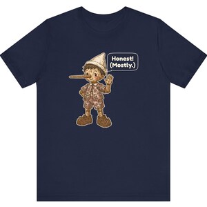 K&ouml;nnte beinhalten: Ein marineblaues T-Shirt mit kurzen &Auml;rmeln und einer Grafik einer Holzpuppe mit langer Nase, die einen Hut, ein Hemd und eine kurze Hose tr&auml;gt. Eine Sprechblase neben der Figur enth&auml;lt den Text "Honest! (Mostly.)" in wei&szlig;en Buchstaben.