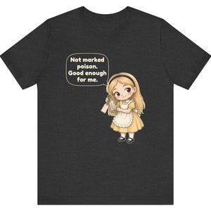 May include: A dark heather gray t-shirt featuring a cartoon illustration of a blonde girl in a yellow dress and white apron holding a glass bottle. A speech bubble above her contains the text: Not marked poison. Good enough for me.
