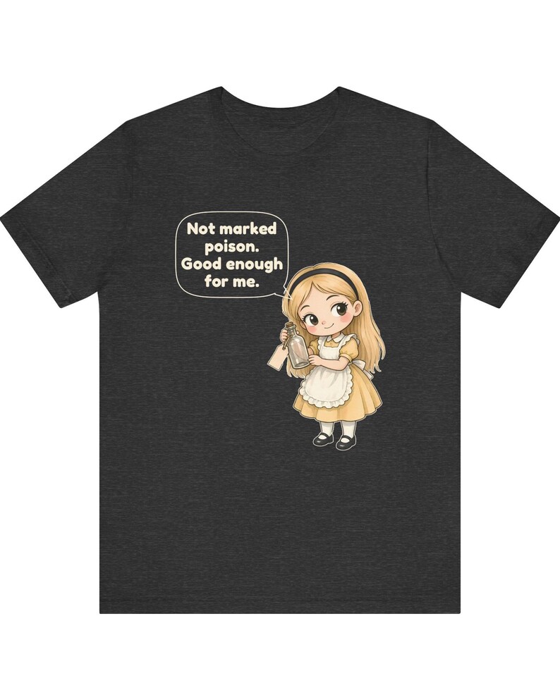 May include: A dark heather gray t-shirt featuring a cartoon illustration of a blonde girl in a yellow dress and white apron holding a glass bottle. A speech bubble above her contains the text: Not marked poison. Good enough for me.