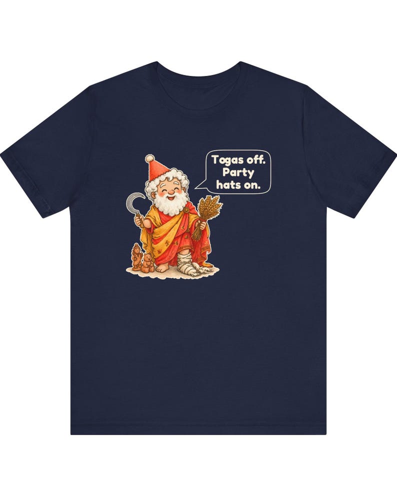 May include: A navy blue t-shirt featuring a graphic of a bearded figure wearing a red party hat and a yellow robe. The figure holds a sickle and a bundle of wheat, with a speech bubble that reads: Togas off. Party hats on.