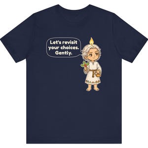 May include: A navy blue t-shirt featuring a cartoon character with a candle flame on their head, holding a sprig of holly and a small teapot. A speech bubble contains the text: Let's revisit your choices. Gently.