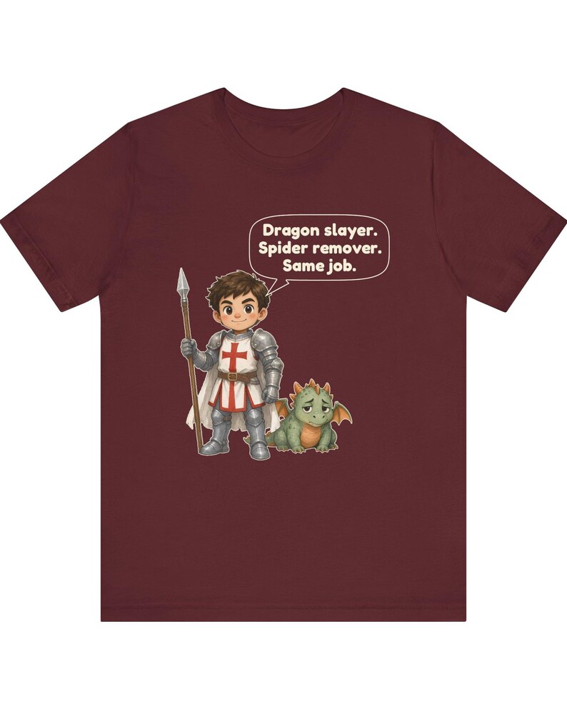 K&ouml;nnte beinhalten: Ein bordeauxrotes Kurzarm-T-Shirt mit einer Grafik eines Cartoon-Ritters in silberner R&uuml;stung, der einen Speer neben einem kleinen gr&uuml;nen Drachen h&auml;lt. Eine Sprechblase &uuml;ber dem Ritter enth&auml;lt den Text: Dragon slayer. Spider remover. Same job.