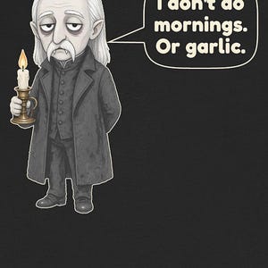 May include: A graphic illustration of a pale, long-haired character with fangs, wearing a dark coat and vest, holding a lit candle in a brass holder. A speech bubble contains the text: I don't do mornings. Or garlic. The background is black.