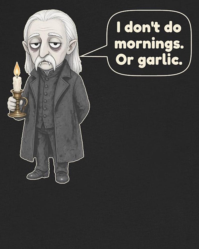 May include: A graphic illustration of a pale, long-haired character with fangs, wearing a dark coat and vest, holding a lit candle in a brass holder. A speech bubble contains the text: I don't do mornings. Or garlic. The background is black.