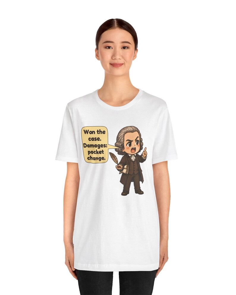 May include: A white t-shirt featuring a cartoon illustration of a historical figure in a brown suit holding a quill. A speech bubble contains the text: Won the case. Damages: pocket change. The design is centered on the chest of the garment.
