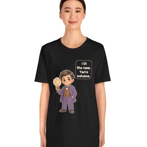 Może przedstawiać: Czarny t-shirt z rysunkową ilustracją osoby w fioletowym garniturze i brązowej kamizelce, trzymającej świecącą żar&oacute;wkę. Dymek obok postaci zawiera tekst: I lit the room. You're welcome.
