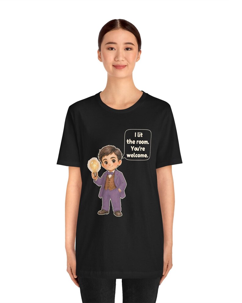 Może przedstawiać: Czarny t-shirt z rysunkową ilustracją osoby w fioletowym garniturze i brązowej kamizelce, trzymającej świecącą żar&oacute;wkę. Dymek obok postaci zawiera tekst: I lit the room. You're welcome.