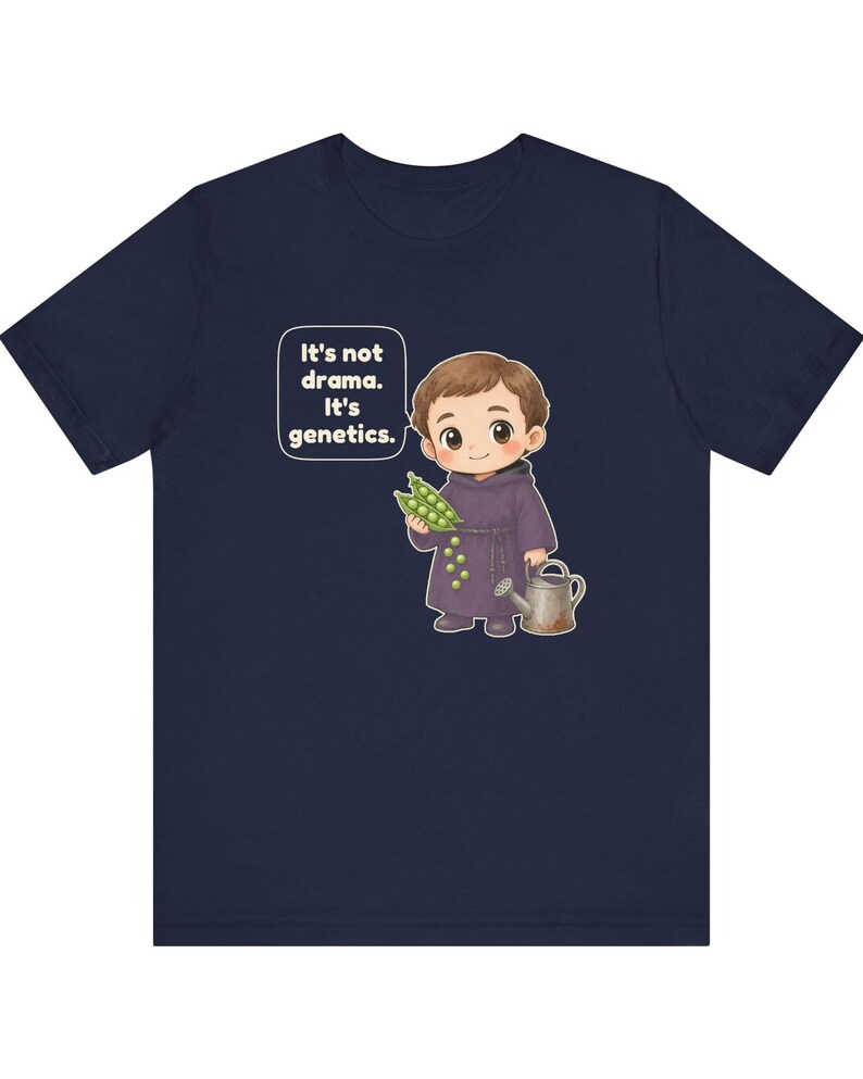 May include: A navy blue t-shirt featuring a cartoon illustration of a monk holding a pea pod and a watering can. A speech bubble next to the character contains the text: It's not drama. It's genetics. The design is centered on the chest.