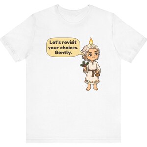 May include: A white t-shirt featuring a cartoon character with a candle flame on their head, holding a sprig of holly and a small kettle. A speech bubble contains the text: Let's revisit your choices. Gently. The character wears a simple tunic.
