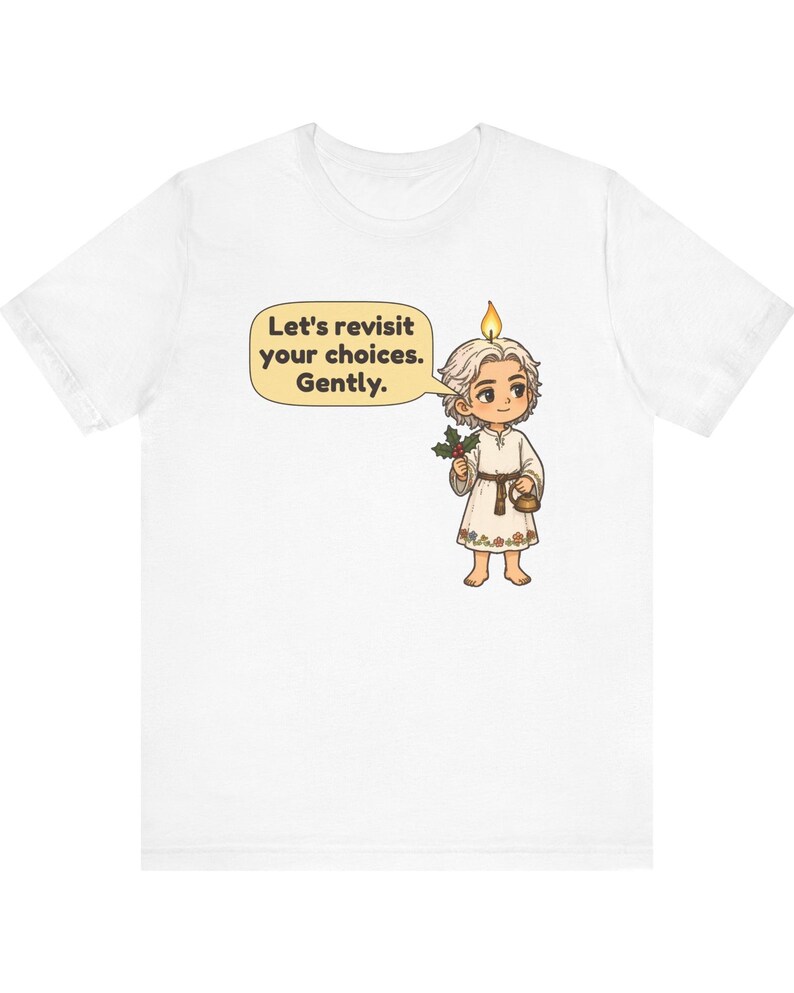 May include: A white t-shirt featuring a cartoon character with a candle flame on their head, holding a sprig of holly and a small kettle. A speech bubble contains the text: Let's revisit your choices. Gently. The character wears a simple tunic.