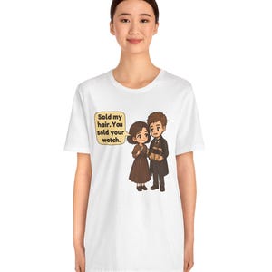 May include: A white t-shirt featuring a cartoon illustration of a couple. The female character has short brown hair and a brown dress, while the male character wears a dark suit. A speech bubble contains the text: Sold my hair. You sold your watch.