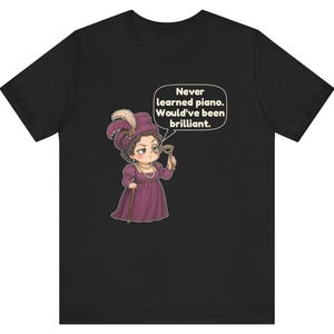 May include: A black t-shirt featuring a cartoon illustration of a person in a purple Victorian-style dress and hat, holding a monocle. A speech bubble above the figure contains the text: Never learned piano. Would've been brilliant.