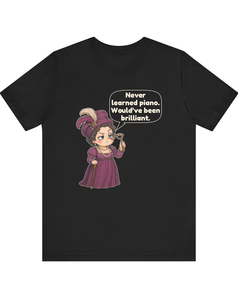 May include: A black t-shirt featuring a cartoon illustration of a person in a purple Victorian-style dress and hat, holding a monocle. A speech bubble above the figure contains the text: Never learned piano. Would've been brilliant.