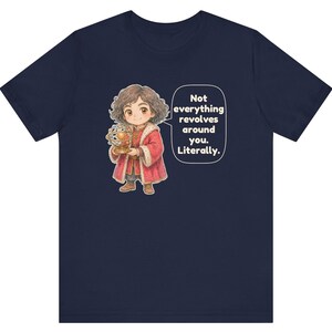 May include: A navy blue t-shirt featuring a cartoon illustration of a person with curly brown hair wearing a red coat and holding an armillary sphere. A speech bubble contains the text: Not everything revolves around you. Literally.