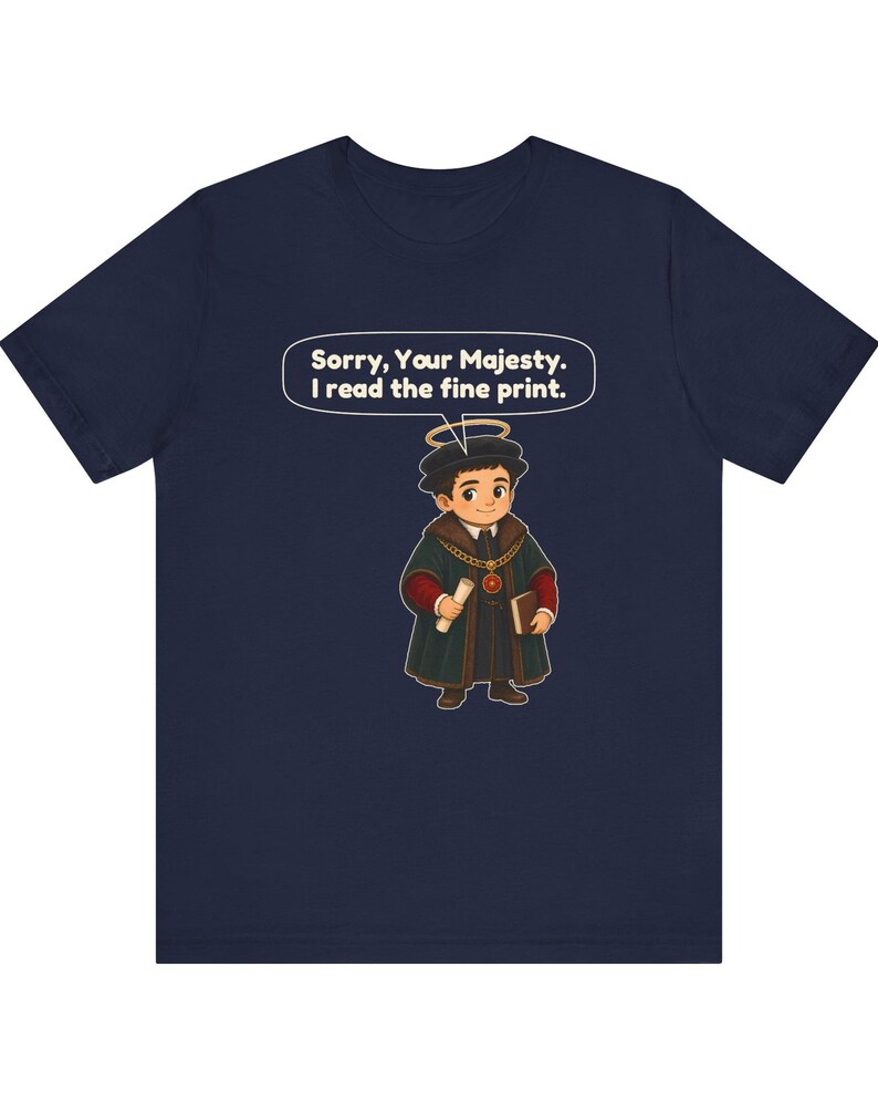 May include: A navy blue t-shirt featuring a cartoon illustration of a person in historical attire with a halo, holding a scroll and a book. A speech bubble above the character contains the text: Sorry, Your Majesty. I read the fine print.