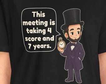 May include: A black t-shirt featuring a cartoon illustration of Abraham Lincoln wearing a top hat and suit, holding a pocket watch. A speech bubble next to him contains the text: This meeting is taking 4 score and 7 years.