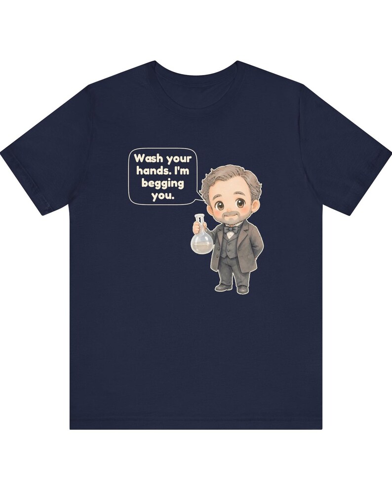 May include: A navy blue t-shirt featuring a cartoon illustration of a man in a suit holding a glass flask. A speech bubble next to the character contains the text: Wash your hands. I'm begging you. The design is centered on the front of the shirt.