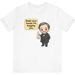 May include: A white short-sleeved t-shirt featuring a cartoon illustration of a person in a black suit and bowtie holding a glass flask. A speech bubble next to the character contains the text: Wash your hands. I'm begging you.